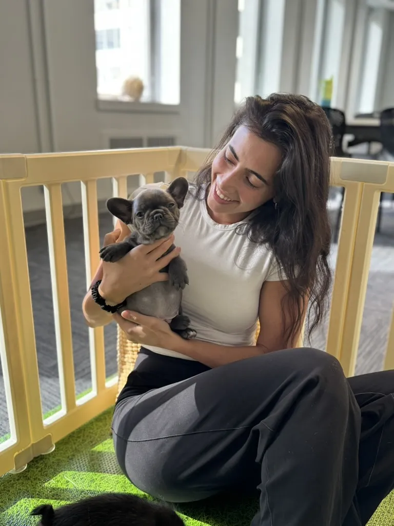 A smiling guest cuddling a French bulldog puppy