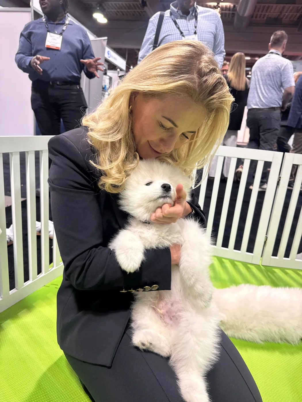 Event attendee cuddling a Samoyed puppy at a trade show booth