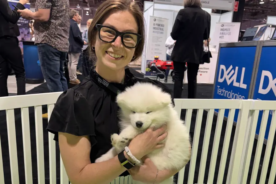 Smiling attendee holding a puppy at the Dell booth